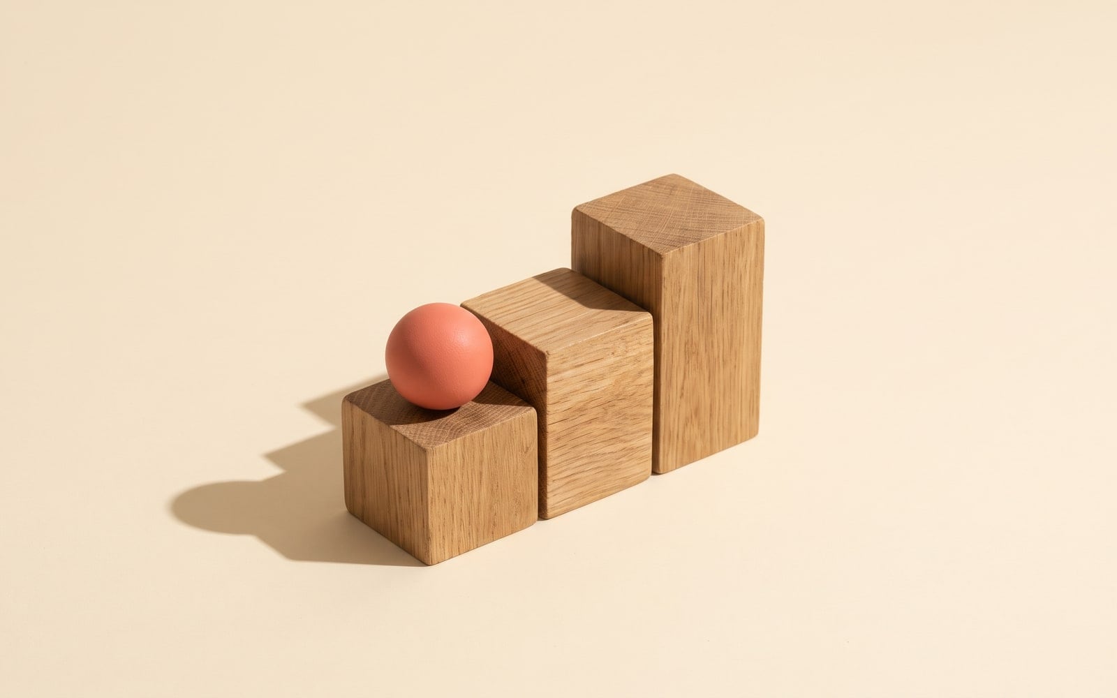 A coral sphere rests on the first of three ascending wooden blocks